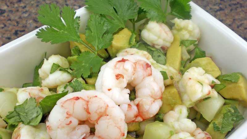 A photograph of Argentine red shirmp ceviche with shrimp, avocado, cucumber, onion, cilantro and lime juice.