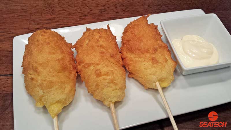 A photograph of Argentine red shrimp corn dogs with a lemon garlic aioli.