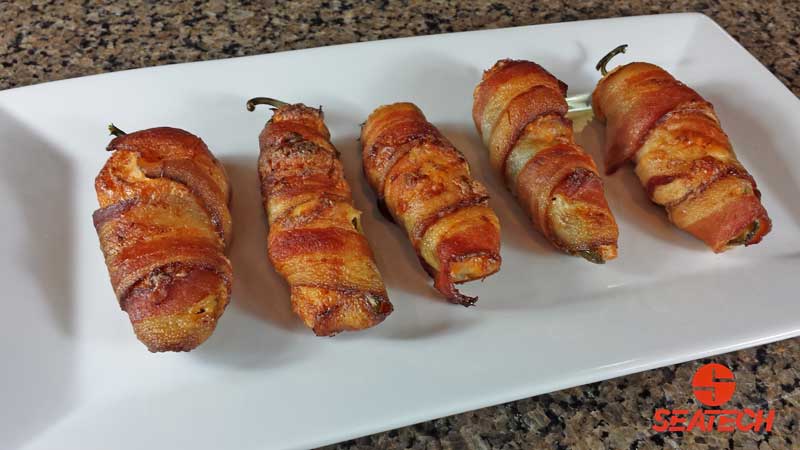 A plate with bacon wrapped crab stuffed jalapeno poppers.