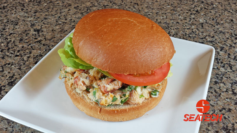 A photograph of a Chilean crab meat burger with lettuce and tomato.