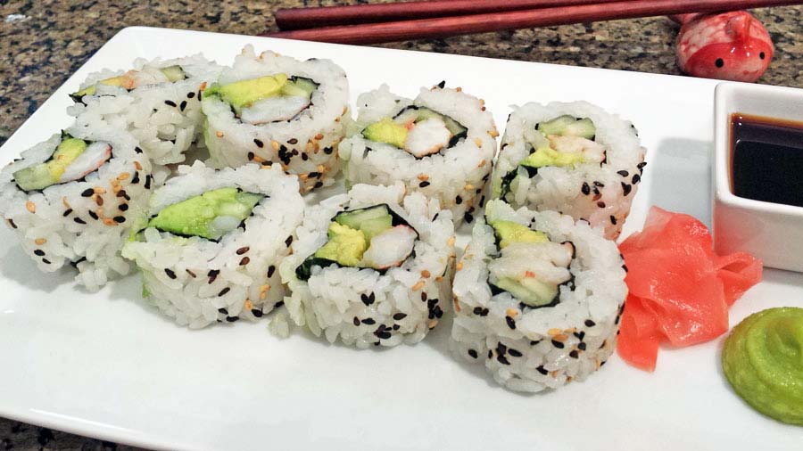 A photograph of freshly langostino lobster sushi rolls with soy sauce, picked ginger and wasabi.
