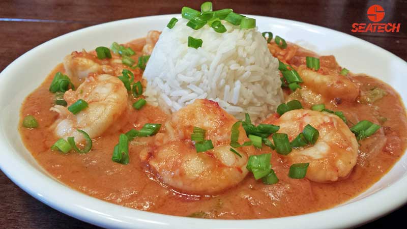 A photograph of Argentine red shrimp gumbo etouffee with steamed rice and sliced scallions.